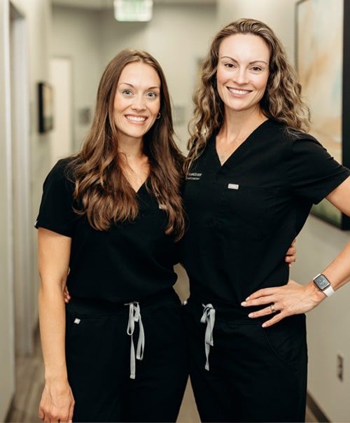 Dr. Langelier & Dr. Leisha smiling and standing oon background of hospital ward