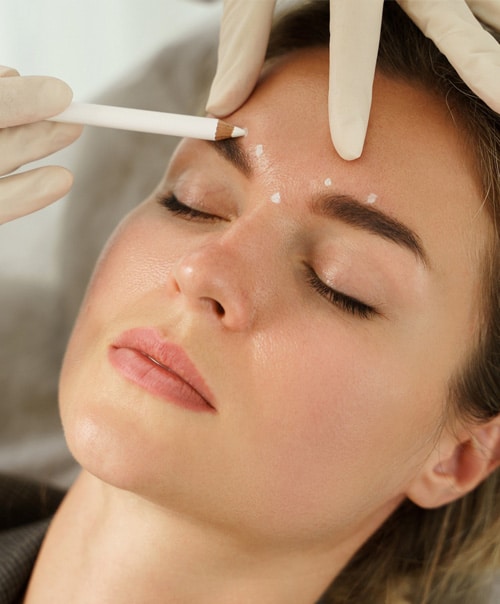 stock image of Doctor making marks on client's face before filler injections in aesthetics medical clinic